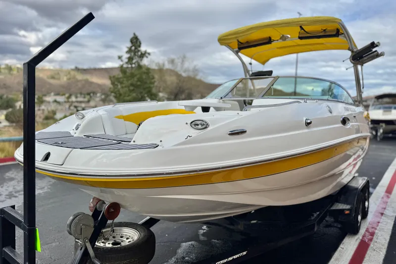 Slide: The Image of 2005 MB 240 V Sportdeck boat with yellow accents on a trailer, parked outdoors. - 3