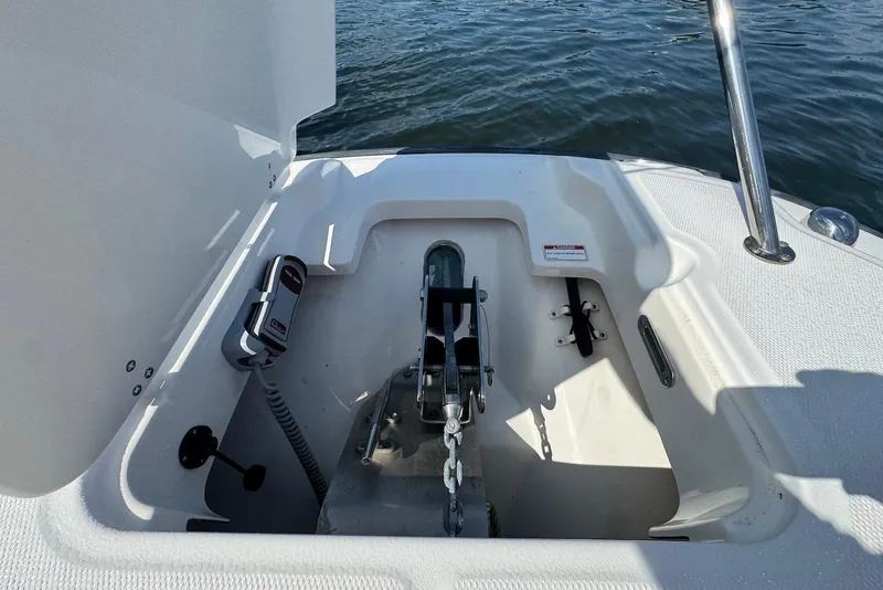Slide: The Image of 2015 Boston Whaler 270 Dauntless anchor compartment with chain and winch, on calm water. - 10