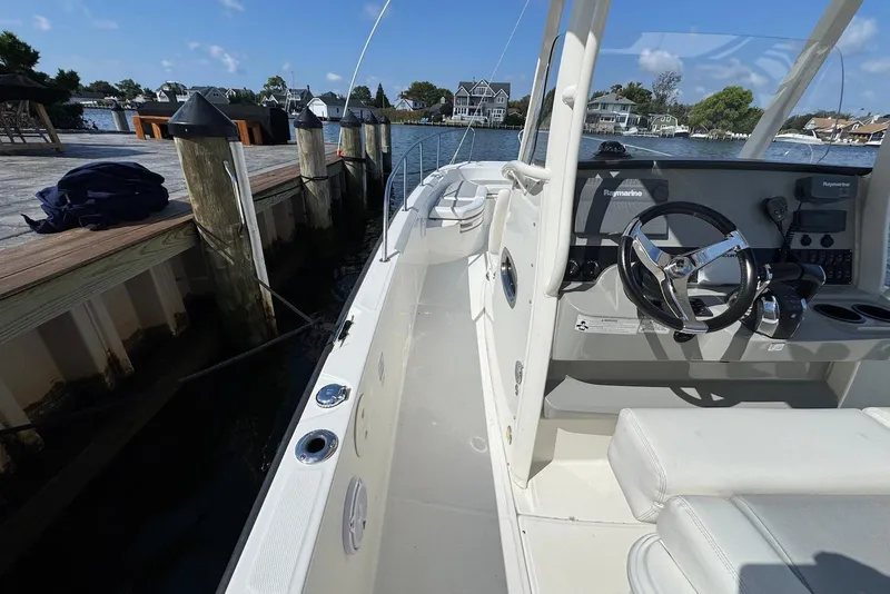 Slide: The Image of 2015 Boston Whaler 270 Dauntless boat docked, featuring steering console and waterfront view. - 9