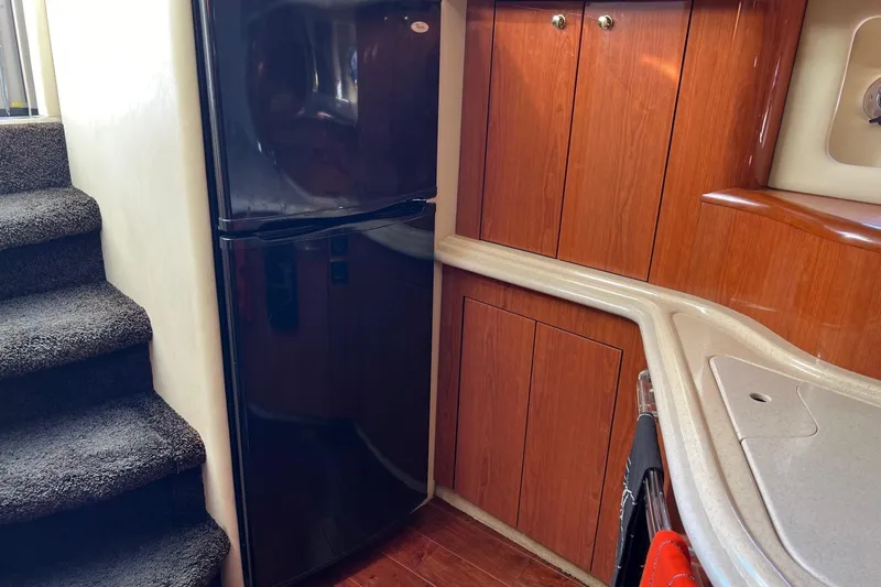 Slide: The Image of Interior of 1998 Sea Ray 540 Sundancer yacht with wood cabinetry and black refrigerator. - 42