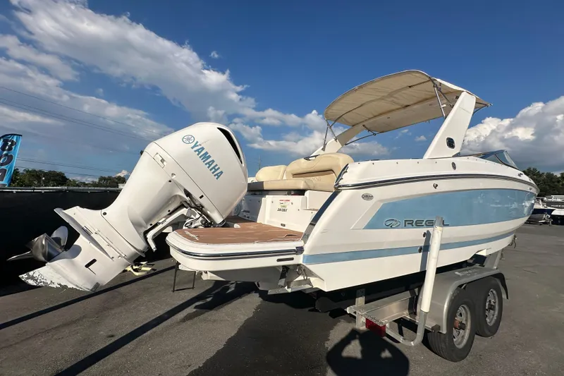 Slide: The Image of 2019 Regal 26 OBX boat with Yamaha outboard motor on trailer, under clear blue sky. - 2