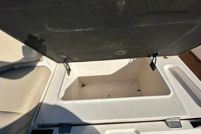 Slide: The Image of Open storage compartment on 2019 Regal 26 OBX boat, featuring beige seating and black lid. - 20
