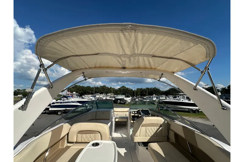 Slide: The Image of 2019 Regal 26 OBX boat interior with canopy, showcasing seating and steering wheel under clear sky. - 25