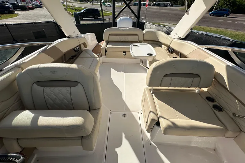 Slide: The Image of 2019 Regal 26 OBX boat interior with beige seating and table, parked outdoors. - 86