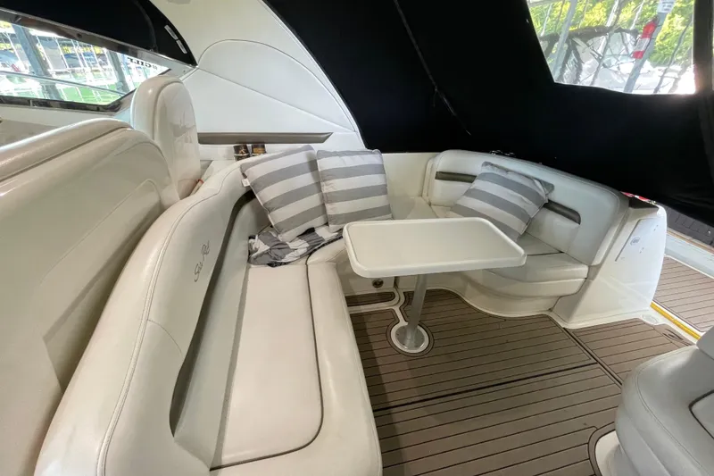 Slide: The Image of 2007 Sea Ray 38 Sundancer interior with white seating, striped pillows, and a small table. - 14