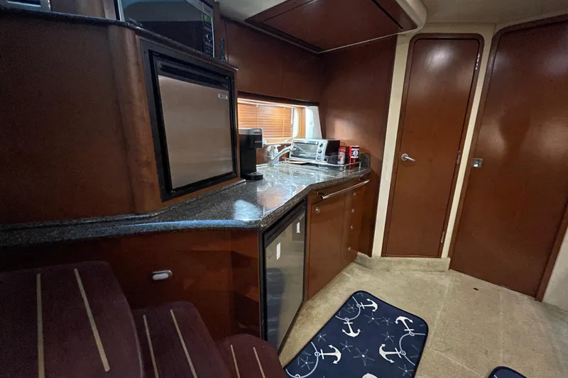 Slide: The Image of 2007 Sea Ray 38 Sundancer yacht interior with kitchenette, featuring wood cabinetry and appliances. - 19