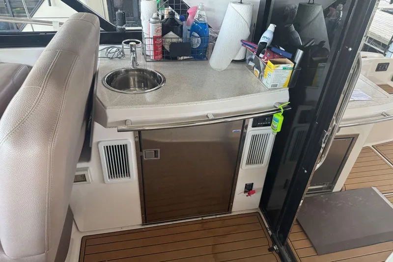 Slide: The Image of 2016 Regal 46 Sport Coupe yacht kitchenette with sink, mini fridge, and countertop essentials. - 23