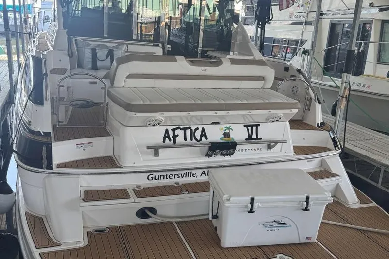 Slide: The Image of 2016 Regal 46 Sport Coupe yacht docked, featuring spacious deck and seating area. - 4