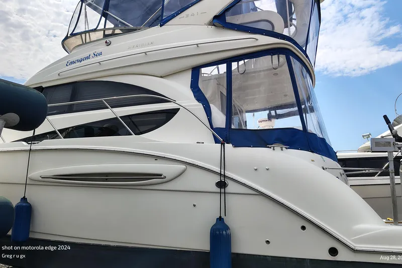 Slide: The Image of 2007 Meridian 341 Sedan yacht docked, featuring sleek design and blue accents under a partly cloudy sky. - 14