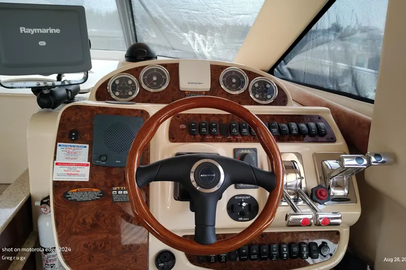 Slide: The Image of 2007 Meridian 341 Sedan helm with Raymarine display, wood accents, and control panel. - 3