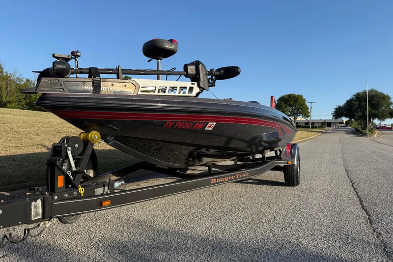 Slide: The Image of 2013 Ranger Z117 boat on trailer by a lake, featuring Evinrude engine. - 2