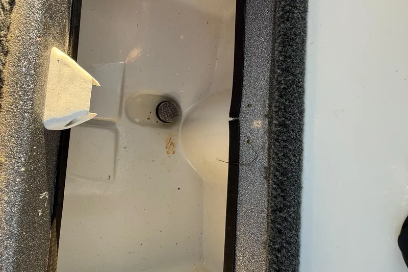 Slide: The Image of Interior compartment of a 2013 Ranger Z117 boat, featuring a drain and textured surfaces. - 52