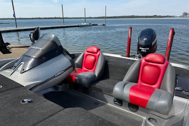 Slide: The Image of 2013 Ranger Z117 boat with red seats, docked by a serene lake. - 59