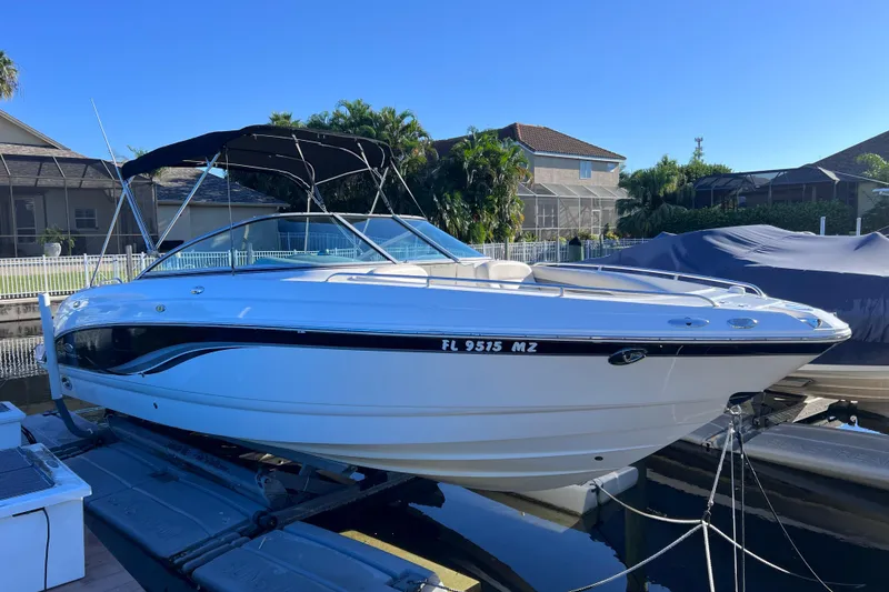 The Image of 2006 Chaparral 256 SSi boat docked, featuring sleek design and black canopy. - 0