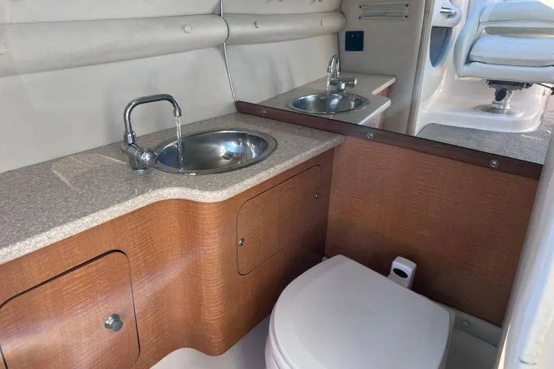Slide: The Image of 2006 Chaparral 256 SSi boat interior with sink, faucet, and toilet in compact bathroom. - 27