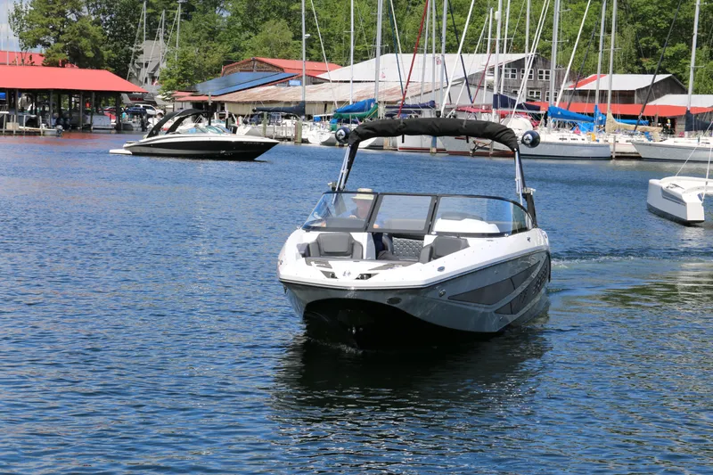 Slide: The Image of 2026 Scarab 255 LX boat cruising in a marina with sailboats and docks in the background. - 1