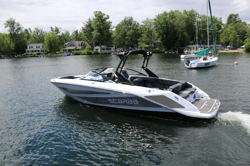 Slide: The Image of 2026 Scarab 255 LX boat cruising on a scenic lake with lush greenery. - 4