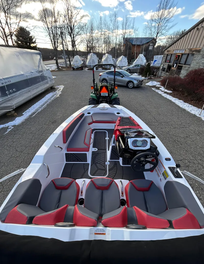 Slide: The Image of 2025 Scarab 165 LX boat with red and gray seating, parked outdoors. - 13