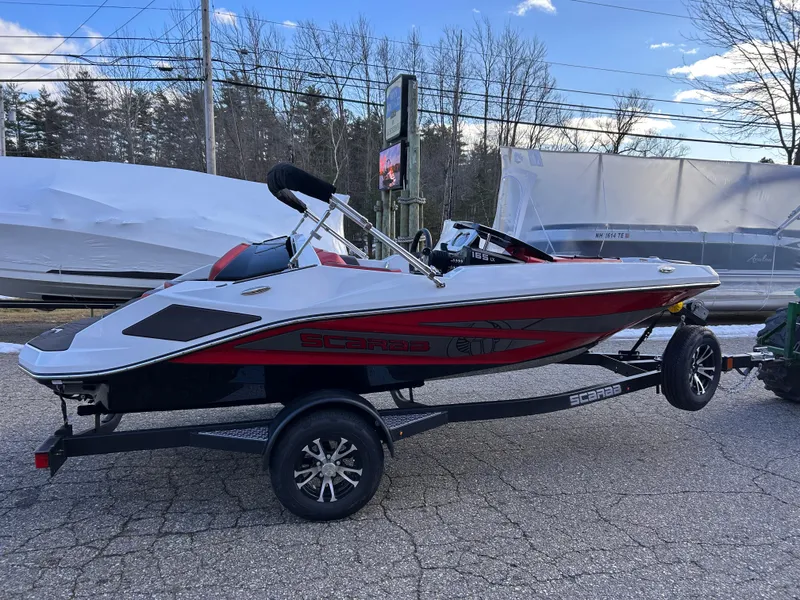 Slide: The Image of 2025 Scarab 165 LX boat on trailer, red and white design, parked outdoors. - 9