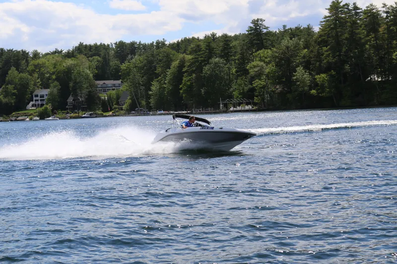 Slide: The Image of 2025 Scarab 165 SE speedboat cruising on a scenic lake with forested shoreline. - 2