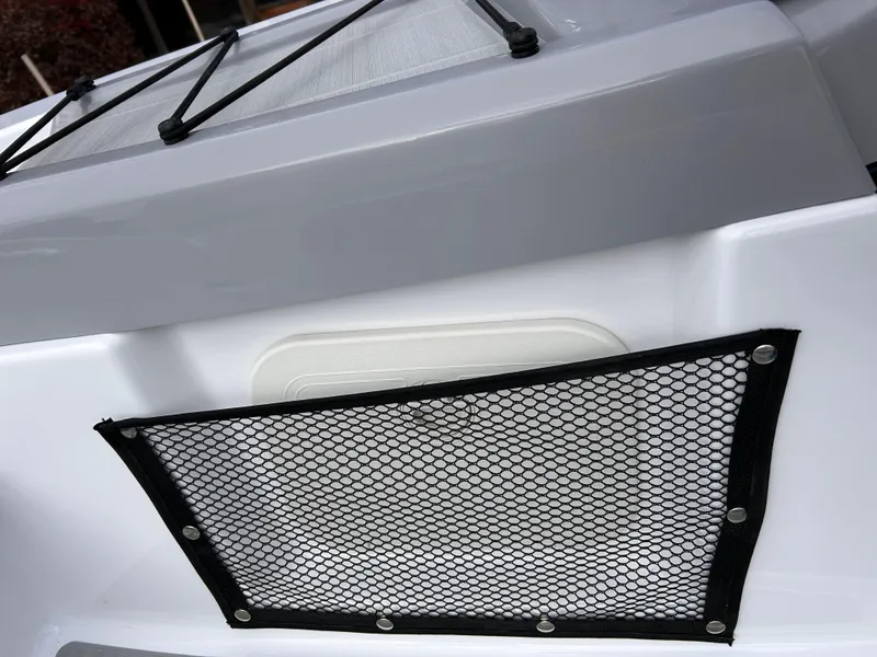 Slide: The Image of 2025 Scarab 165 SE boat storage compartment with gray cushioned seating. - 25