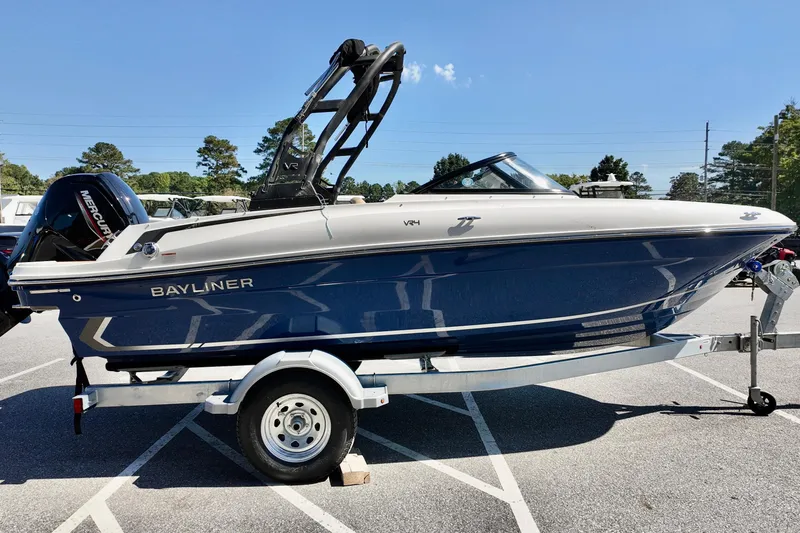 Slide: The Image of 2025 Bayliner VR4 Bowrider OB on trailer, parked outdoors under clear blue sky. - 2