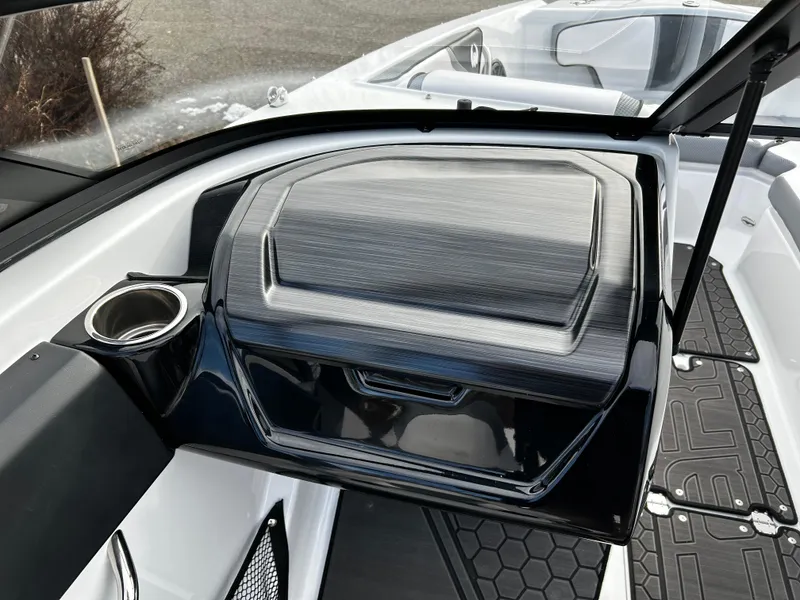 Slide: The Image of 2024 Scarab 215 Wake LE boat interior with storage compartment and cup holder. - 21