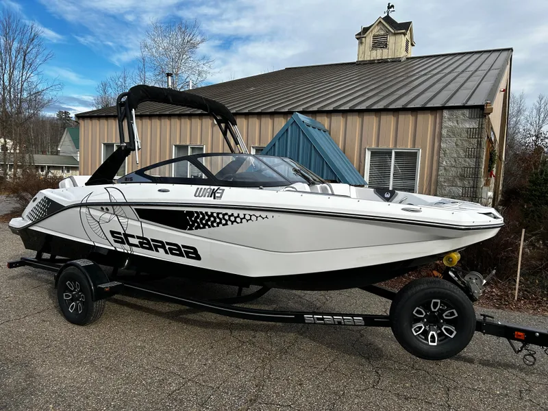 Slide: The Image of 2024 Scarab 215 Wake LE boat on a trailer in front of a building. - 3