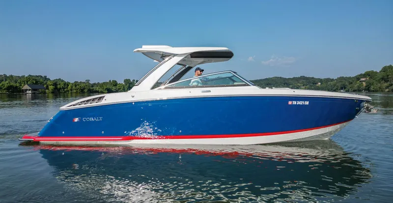 Slide: The Image of 2023 Cobalt R33 boat cruising on a calm lake under a clear blue sky. - 9