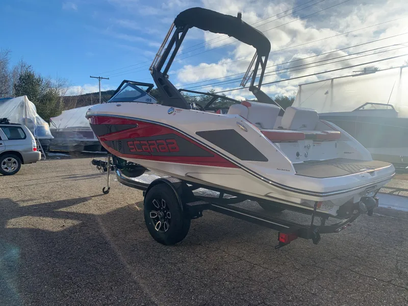 Slide: The Image of 2023 Scarab 195 ID boat on a trailer, red and white exterior, parked outdoors. - 4