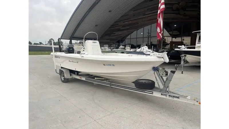 Slide: The Image of 2005 Sea Fox 205 Bay Fisher boat on trailer, parked near a large hangar. - 6