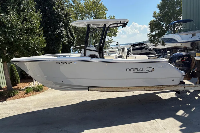 Slide: The Image of 2022 Robalo R230 Center Console boat on a lift, outdoors under a blue sky. - 1