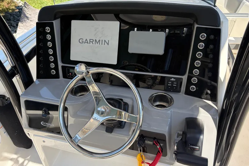 Slide: The Image of 2022 Robalo R230 Center Console boat interior with cushioned seating and engine view. - 9