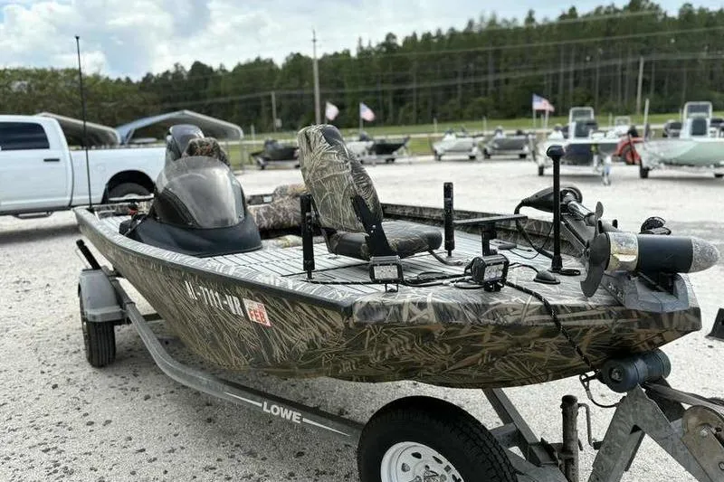 Slide: The Image of 2016 Lowe Stinger 175C fishing boat on trailer, camo design, parked outdoors. - 11