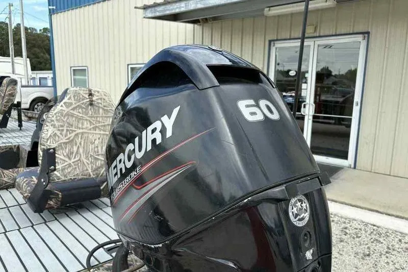 Slide: The Image of 2016 Lowe Stinger 175C with Mercury 60 outboard motor, camo seats, outdoor setting. - 2