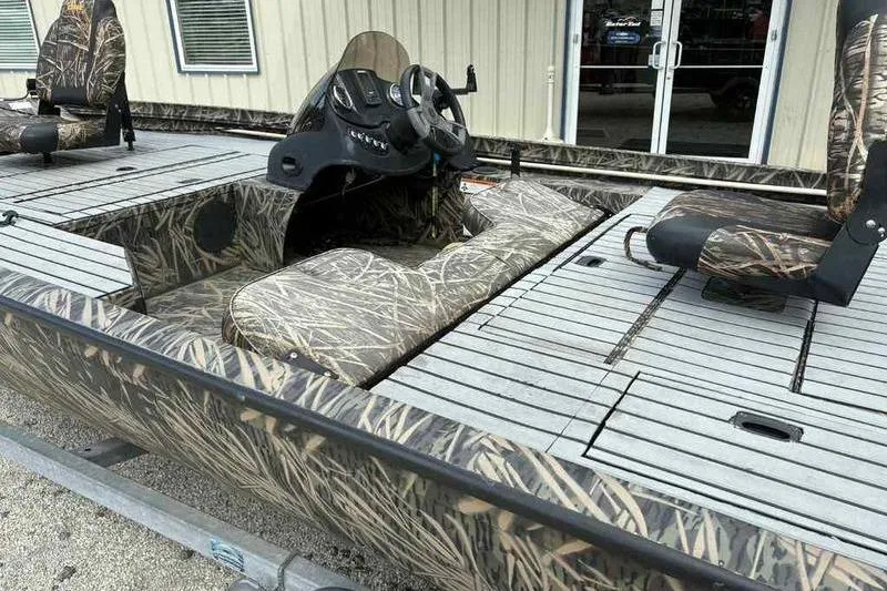 Slide: The Image of 2016 Lowe Stinger 175C boat with camouflage design and seating, parked outdoors. - 6