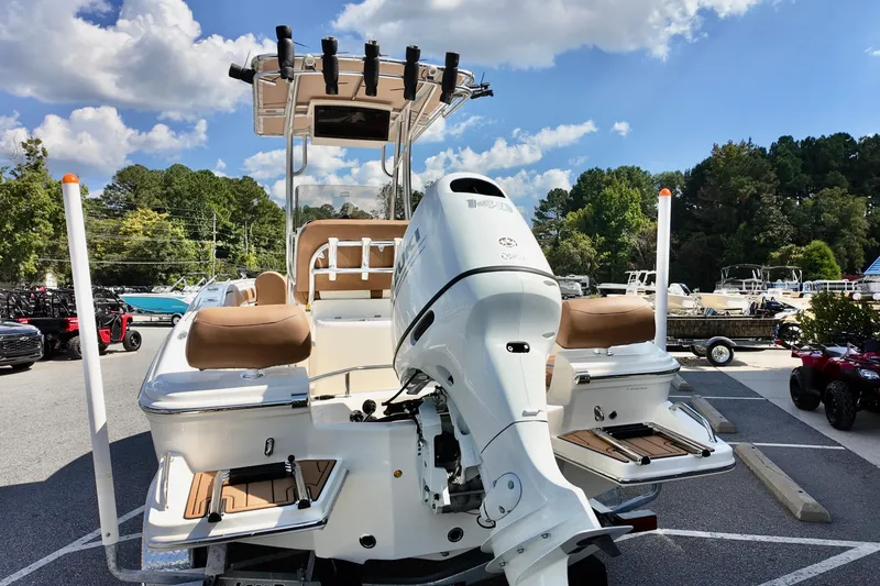 Slide: The Image of 2026 Pioneer 202 Sportfish boat with outboard motor, parked outdoors under a blue sky. - 13