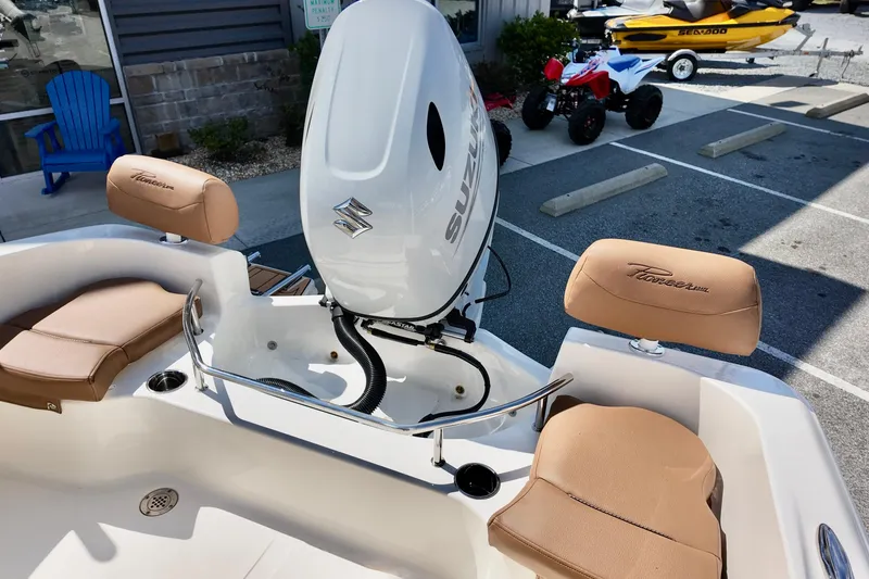 Slide: The Image of 2026 Pioneer 202 Sportfish boat with Suzuki engine, tan seating, and outdoor display. - 4