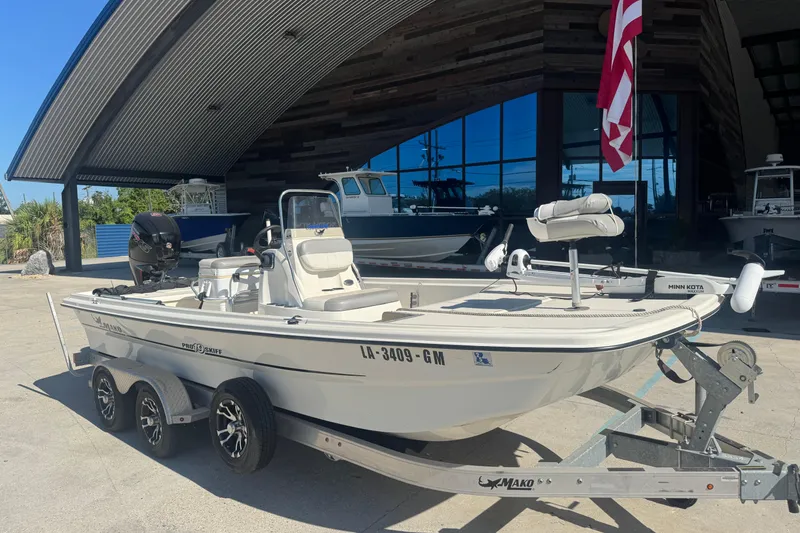 Slide: The Image of 2021 Mako Pro Skiff 19 CC boat on trailer, parked outside a modern building. - 7