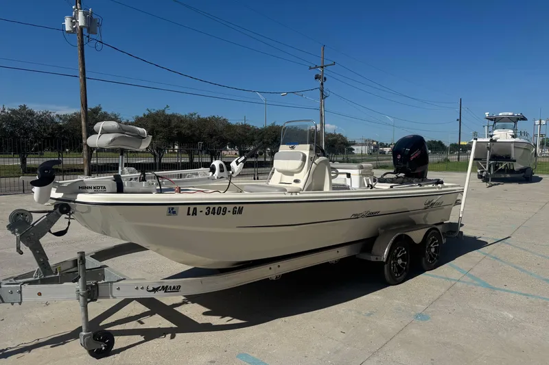 Slide: The Image of 2021 Mako Pro Skiff 19 CC boat on trailer, parked outdoors under clear blue sky. - 8