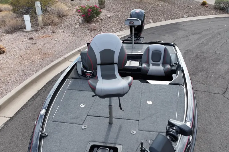 Slide: The Image of 2024 Ranger Z518 boat with gray seating and fishing deck, parked on roadside. - 3