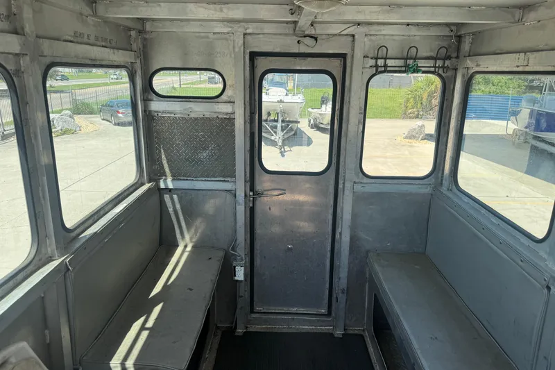 Slide: The Image of Interior of a 2010 Custom Aluminum Work Boat 33, featuring metal benches and windows. - 14