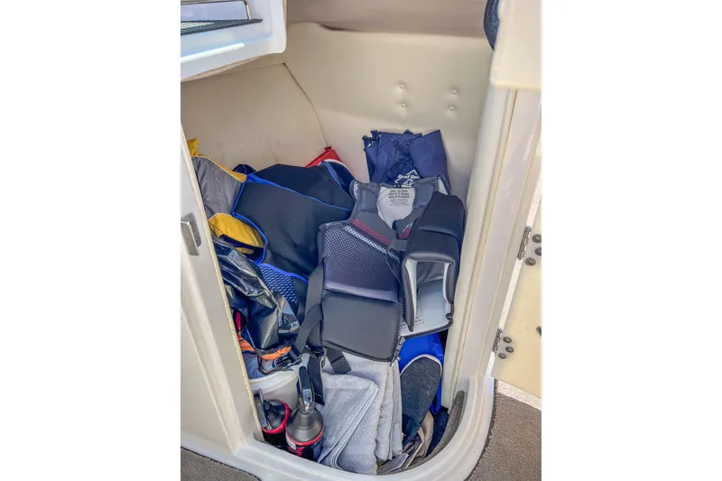 Slide: The Image of Storage compartment in a 2003 Cobalt 240 boat, filled with life jackets and gear. - 15
