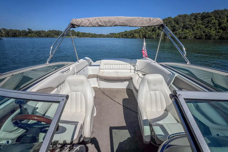 Slide: The Image of 2003 Cobalt 240 boat interior with white seating on a serene lake. - 23