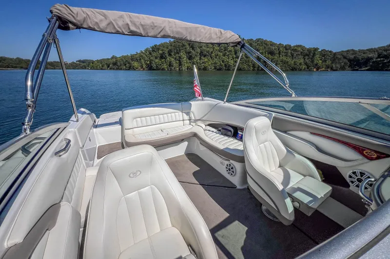 Slide: The Image of 2003 Cobalt 240 boat interior with white seating, on a serene lake. - 24