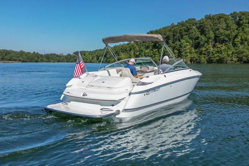 Slide: The Image of 2003 Cobalt 240 boat cruising on a lake with American flag, surrounded by trees. - 3