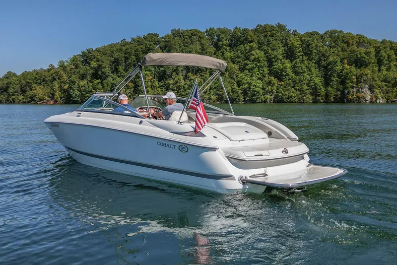 Slide: The Image of 2003 Cobalt 240 boat cruising on a lake with lush green forest backdrop. - 4