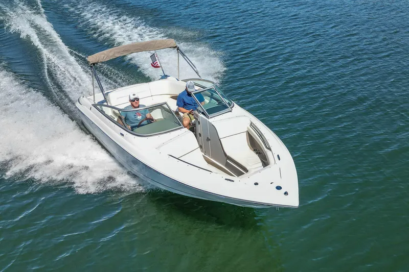 Slide: The Image of 2003 Cobalt 240 boat cruising on clear blue water with two passengers. - 7