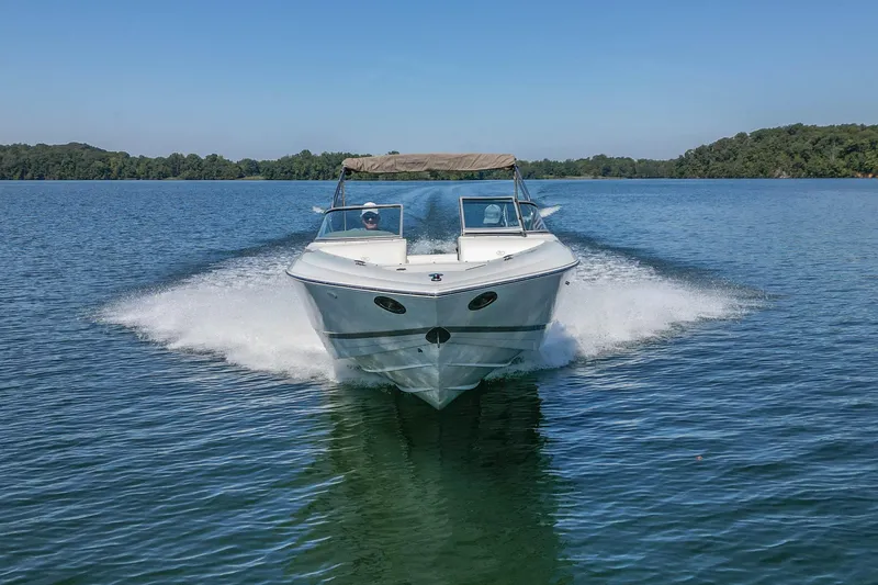 Slide: The Image of 2003 Cobalt 240 boat cruising on a serene lake under clear blue skies. - 8