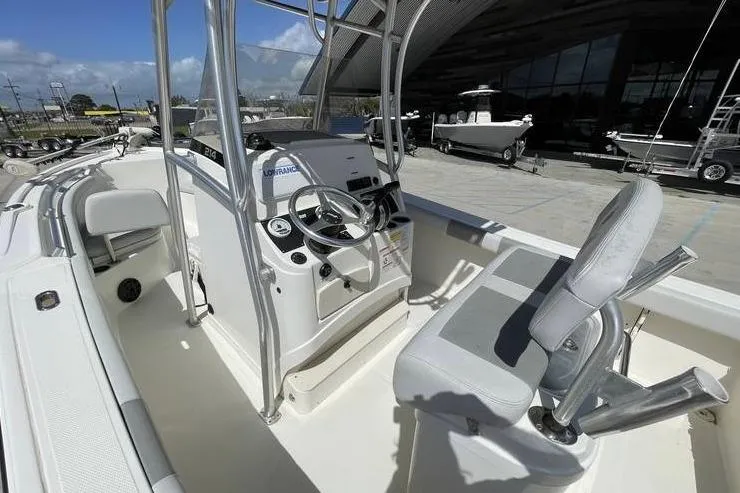 Slide: The Image of 2020 Mako 214 Center Console boat with steering wheel and seating, docked outdoors. - 11